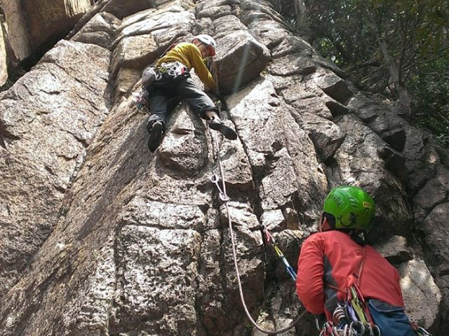 岩壁を登る男性と、ビレイする女性。