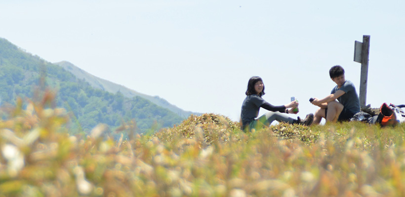 登山中に野原でくつろぐ男性と女性